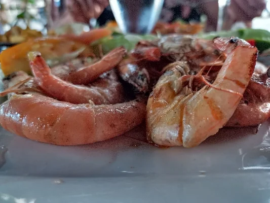 Plato de camarones recién preparados, acompañados de vegetales y especias, servidos en un restaurante.